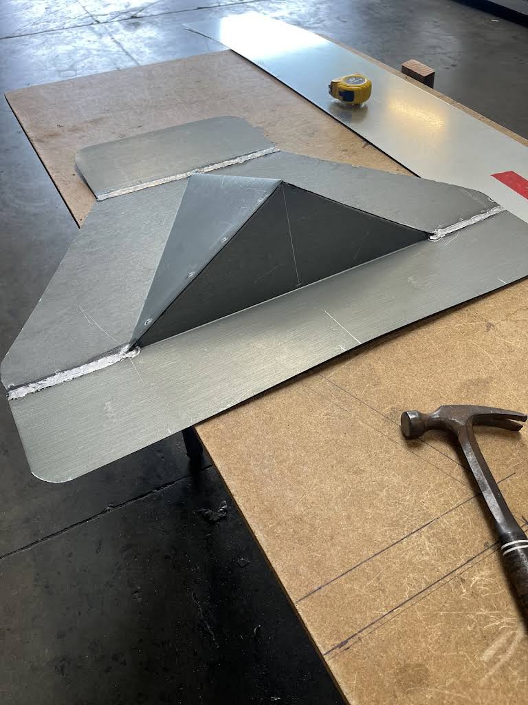 Angular metal flashing assembled on a flat sheet on a workshop bench