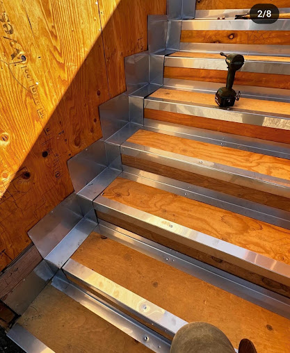 Metal flashing fitted along unfinished wooden stairs